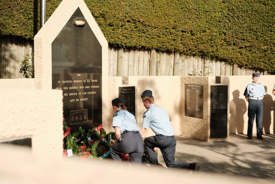 Two people knelt down laying a wreath