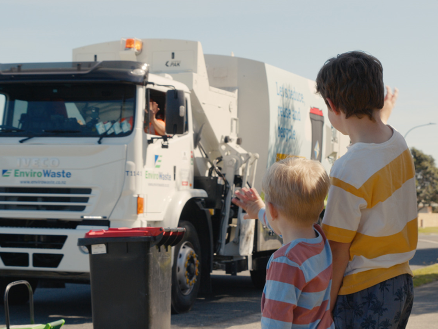 Children waving to collection truck drivers